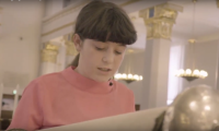 En pige læser op af en torahrulle inde i synagogen
